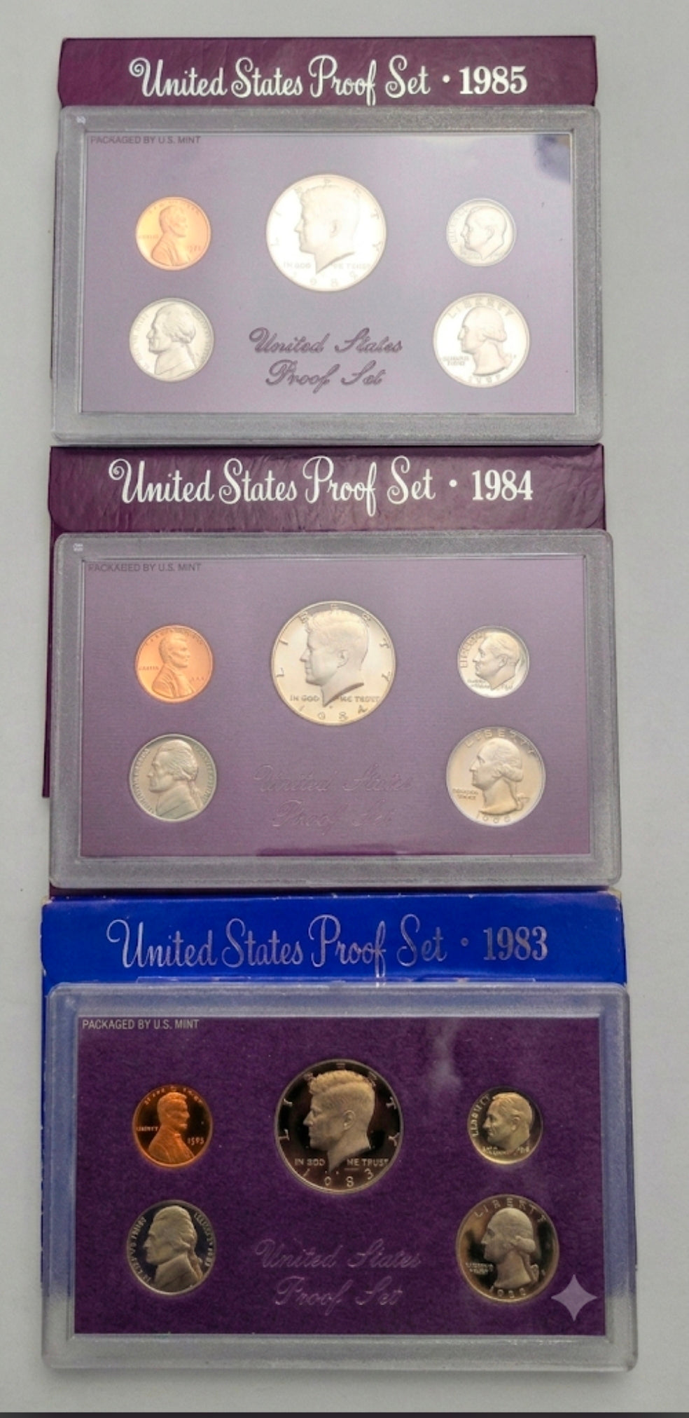 United States Proof Set coins from 1983, 1984, and 1985.